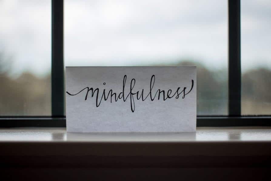 The writing “mindfulness” on the paper that’s on the peaceful windowsill.